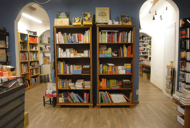 Librería Casa Anita por dentro. Pintada de azul, con dos puertas en arco, y con muchos libros a la vista en las estanterías. Ilustra lo que encontraréis si váis.